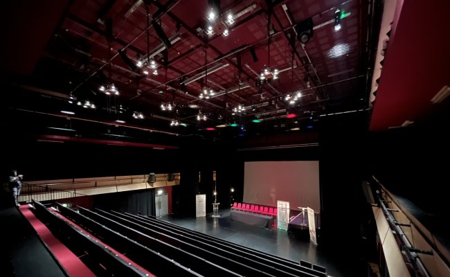 The auditorium at Bernie Grant Arts Centre: raked rows of red seats facing an empty stage under a rig of lights.
